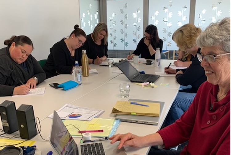 Six team members are sitting around a table reviewing data