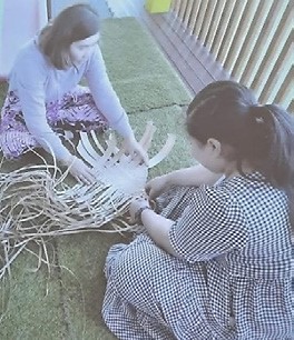 This is a photo of two women sitting and weaving