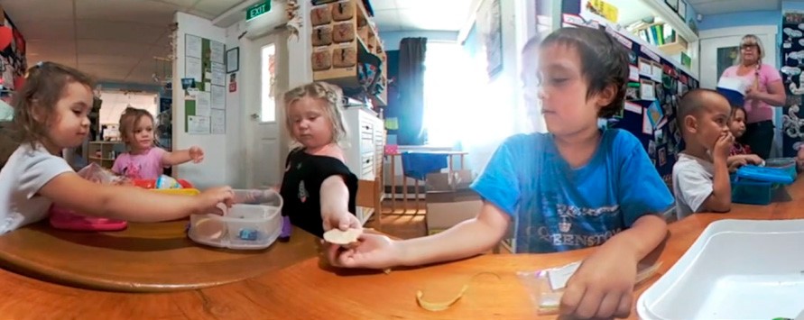 This is a photo of four children at a table, sharing food