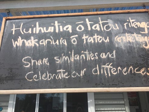 This is a photo of a blackboard with some text in Māori, followed by this statement . . .  Share similarities and celebrate our differences