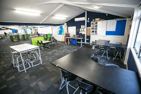 A photo of tables, chairs and notice boards in the class room