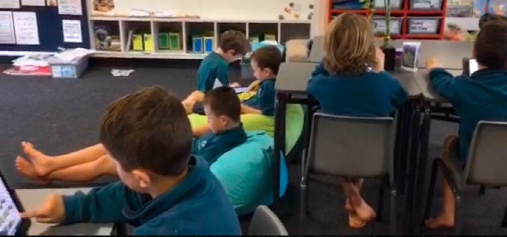 This photo is of several students. Some of them are sitting at a table. Others are sitting on bean bags