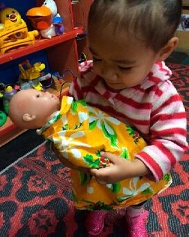 This is a photo of a toddler holding a doll