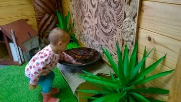 This is a picture of a pre-schooler bending down to the bowl to touch the water