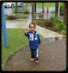 This is a closer shot of the boy walking away from the puddle and smiling