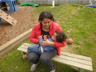 This is a picture of a woman sitting on a bench, holding a child in her arms