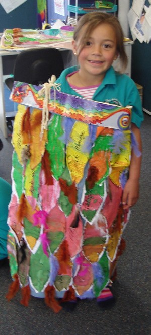 This is a picture of a girl (perhaps five years old) proudly displaying a brightly coloured korowai