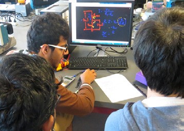 This is a photo of three people gathered around a computer monitor