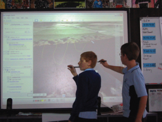 Two students are using styli to interact with a white board