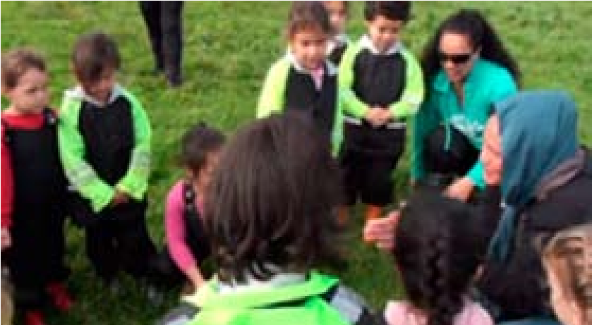 This is a picture of about a dozen children and several adults gathered in a circle