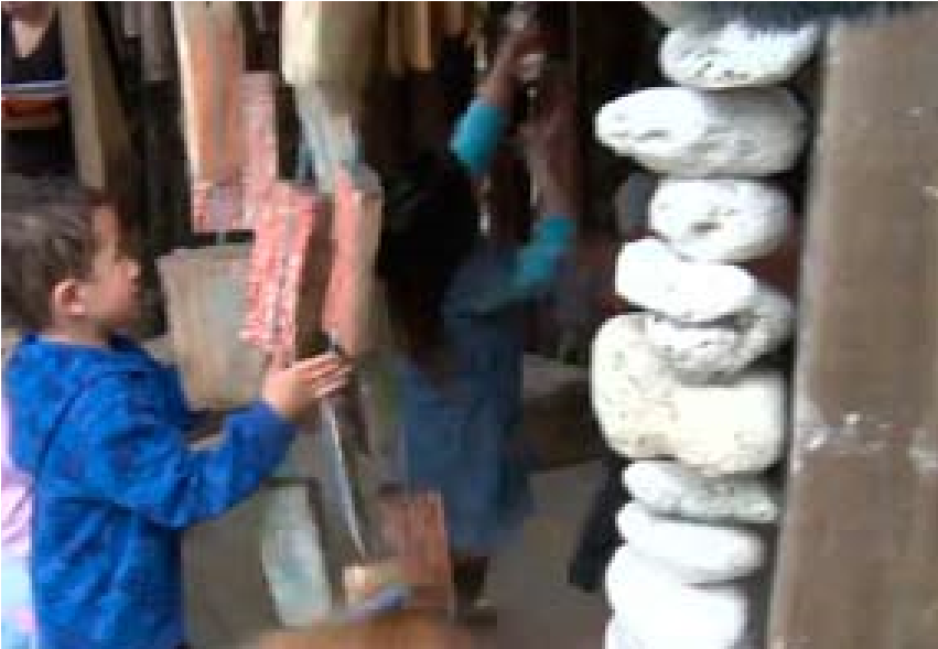 A photo of two children in what appears to be large musical chimes