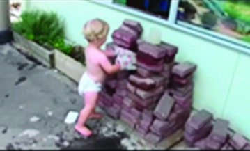 This is the same child standing next to a pile of what appears to be bricks