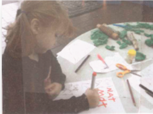 This is a picture of a pre-schooler sitting at a table writing letters of the alphabet