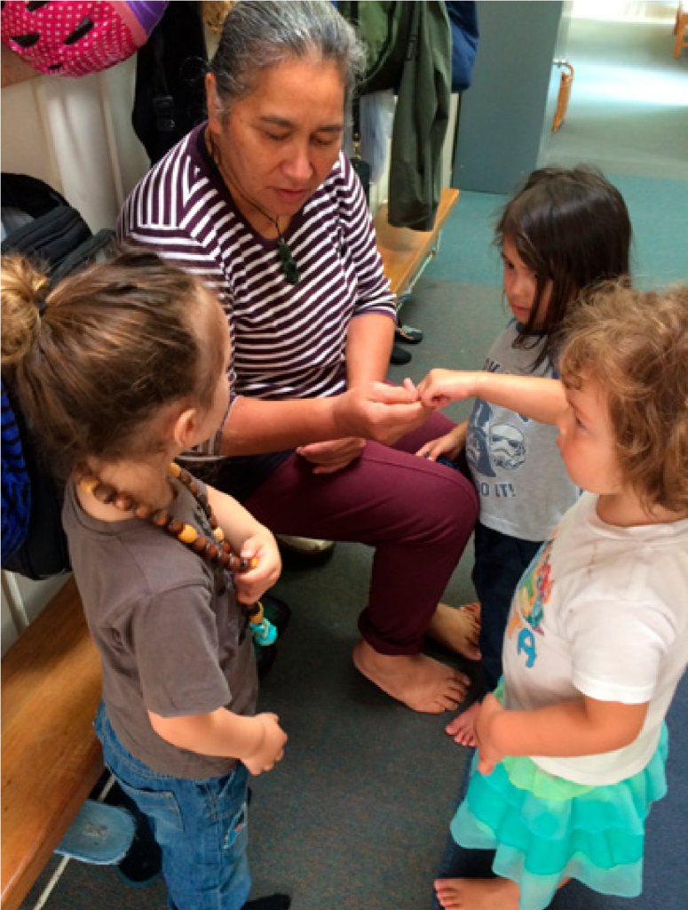 This is a photo of a person surrounded by four children. They are engaged in a discussion