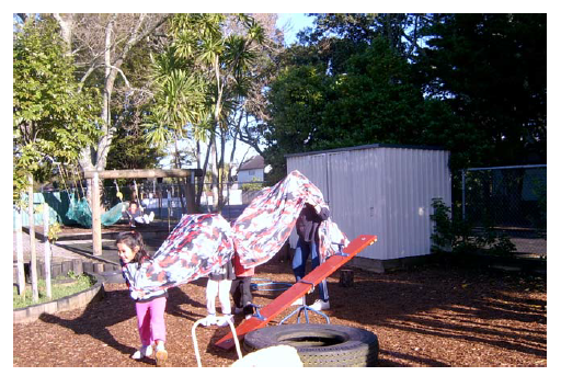 A photo with several children with what could be a sheet over their heads, pretending to be a dragon