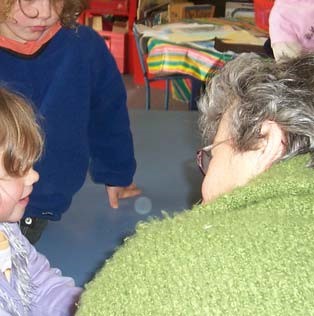 A teacher crouching down to talk to two students