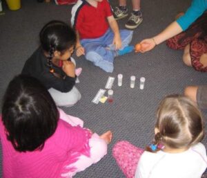 4 students and the teacher sitting on the carpet focussing on a taks