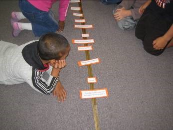 Students lying on the floor looking at artefacts