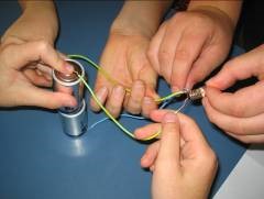 A close-up photo of several pairs of hands joining wires together