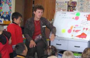 A student and teacher leading a lesson in front of some children seated on the mat