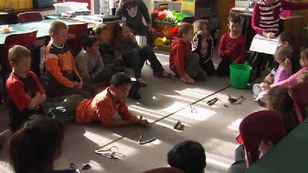 A photo of students lying on the floor looking at tongs