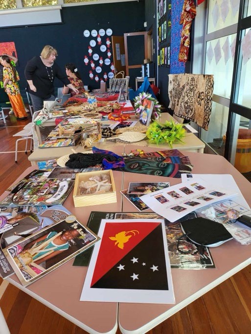 This is a photo of a table covered in PLD resources, including a flag, photos and head-dress