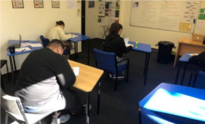 This is a picture of several rangatahi siting at desks in a classroom, writing