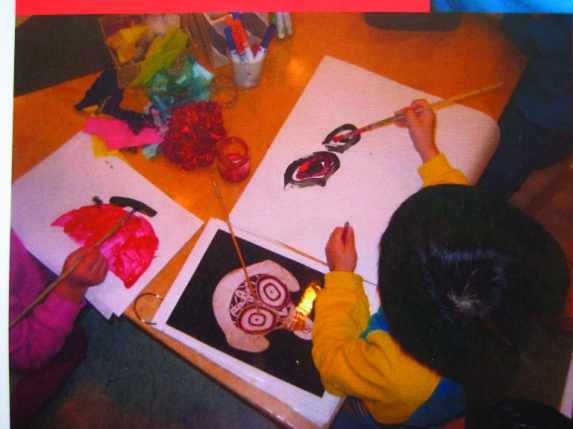 A photo of two children paining at a table